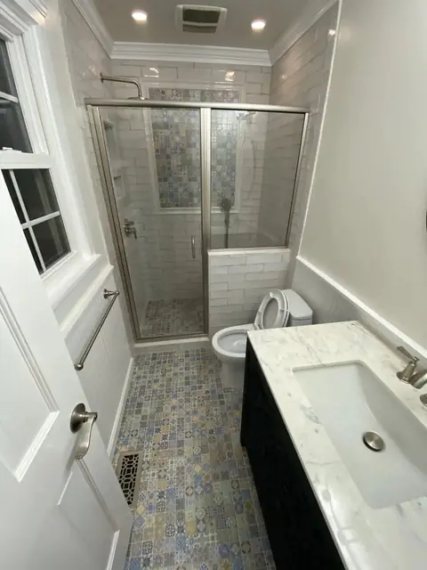 Bathroom with glass shower and blue patterned floor tile