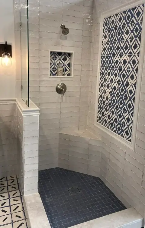 Tiled walk-in shower with bench and patterned accent wall